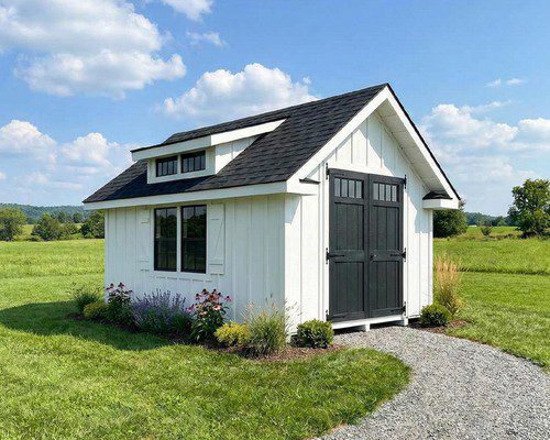White backyard structure with black doors and a landscaped path