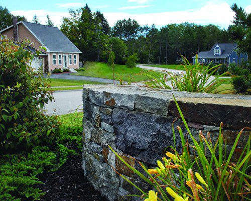 Natural stone retaining wall with yellow daylilies in a Vermont landscape
